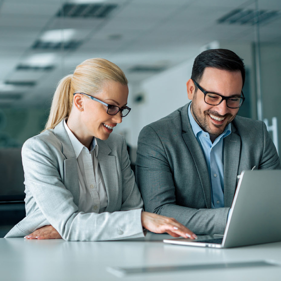 Due persone sorridenti lavorano sullo stesso computer portatile